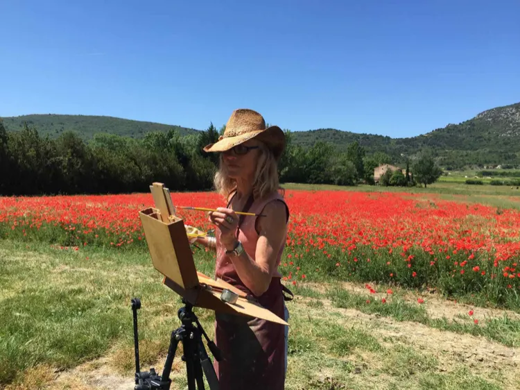 A painter working beside a field of red poppies in Provence